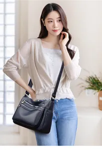 Détail du sac bandoulière en cuir noir texturé avec plusieurs poches zippées sur modèle