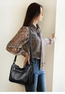 Detail of black multi-pocket tote bag showing silver zippers and wide shoulder strap