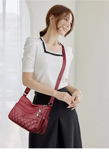 Détail du sac bandoulière bordeaux avec motifs matelassés et design multi-poches
