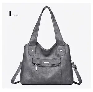 Detail of dark gray soft faux leather handbag with silver zippers and removable strap