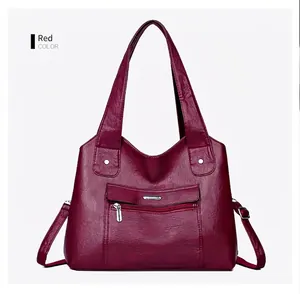 Detail view of red pebbled faux leather tote bag with silver zipper and double handles