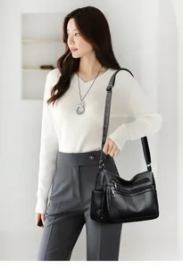 Close-up of a black multi-zipper tote bag with pebble leather texture worn by a model