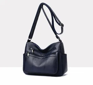 Detail of blue pebbled leather tote with multi-zipper pockets and adjustable strap