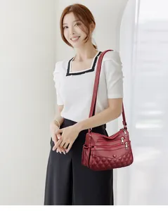 Détail du sac bandoulière bordeaux avec compartiments zippés et motif matelassé chic