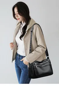 Vue détaillée du sac bandoulière en cuir noir avec plusieurs poches zippées argentées
