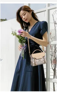 Détail d'un sac à main élégant avec broderie florale bleue et fermoir cygne doré