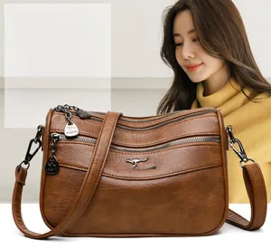 Detail view of brown leather bag featuring three zipper pockets and a metal kangaroo logo