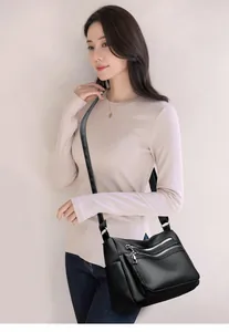 Détail d'un sac bandoulière noir avec poches zippées multiples et texture cuir grainé