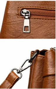 Detailansicht der braunen Ledertasche mit silbernem Metallreißverschluss und D-Ring-Beschlägen
