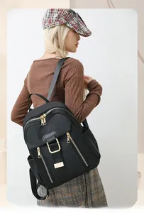 Detailed side view of a waterproof black nylon backpack with gold metal zippers and leather tag