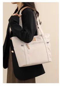Minimalist cream tote bag with brown handles shown on shoulder for daily commute use