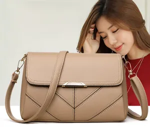 Detail showing apricot leather flap bag with V-shaped stitching and gold metal bar