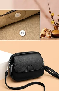 Detail of lychee pattern leather crossbody bag with secure magnetic buckle and dual zippers
