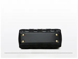 Détail du fond d'un sac en cuir noir avec clous de protection dorés et motif matelassé