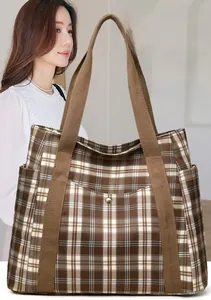 Detail of checkered tote bag with golden snap button and wide woven strap for daily use