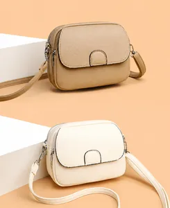Detail view of khaki and beige crossbody bags with pebble leather texture and metallic zipper