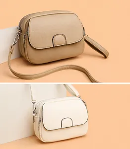 Detail of lychee pattern leather crossbody bags in khaki and cream white finishes