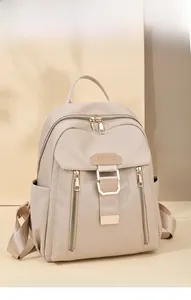 Detailed view of beige waterproof nylon backpack featuring gold zippers and side pockets