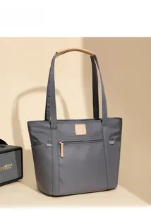 Detail view of a large grey nylon tote bag with leather handles and side pockets