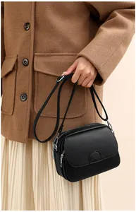 Detail of black pebbled leather crossbody bag with silver zippers and multi-compartments