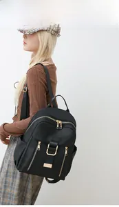 Modern black waterproof nylon backpack for women featuring stylish gold zippers and pockets