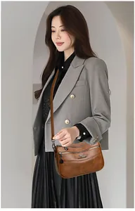 Detail of a dark brown multi-layer crossbody bag with three zippers and kangaroo metal logo