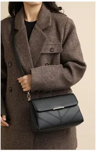 Close-up of black litchi grain leather crossbody bag with V-shaped stitching and metal lock