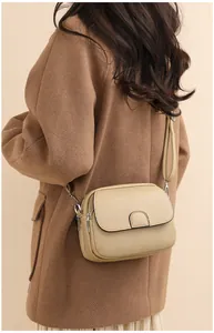 Detail view of khaki lychee leather crossbody bag with silver hardware on model