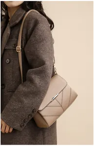 Detail of a beige leather crossbody bag with V-shaped stitching and silver clasp
