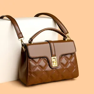 Sac à main en cuir matelassé marron avec fermoir doré sur un présentoir géométrique