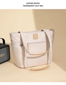 Detail view of leather handles and multi-pocket design on a waterproof beige tote bag