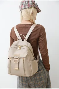 Detail of a beige waterproof nylon backpack featuring gold zippers and a minimalist design