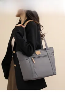 Detail shot of a dark grey waterproof nylon tote bag with front zipper and side pocket