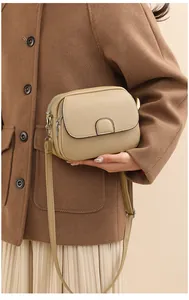 Detailed macro of khaki lychee grain leather crossbody bag with decorative buckle