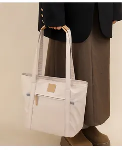 Detailed view of tote bag featuring side pockets and reinforced brown leather handles