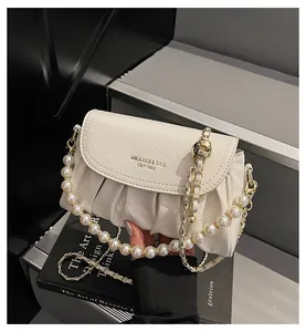 Détail du sac nuage plissé crème avec chaîne de perles et logo de marque gravé
