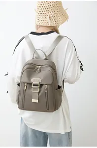 Detail of khaki waterproof nylon backpack with gold zippers and vertical front pockets