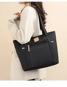 Close-up of black nylon tote bag with front zipper pocket and brown leather label