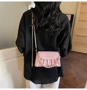 Détail du sac nuage plissé rose avec bandoulière perle et chaîne dorée sur mannequin