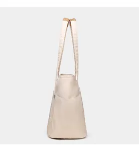 Detail of minimalist tote bag showing side pocket and reinforced brown strap attachment