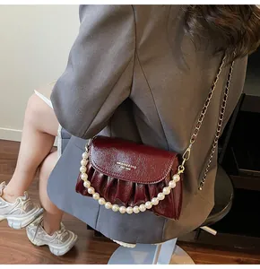 Détail du sac nuage plissé bordeaux avec bandoulière en perles et texture cuir poli