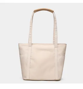 Detail view of large nylon tote bag featuring leather handles and functional front pocket