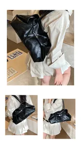 Detail view of black vintage tote bag with glossy leather texture and slim shoulder strap