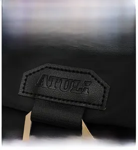 Detail of waterproof black nylon backpack showing embossed brand logo and gold buckle