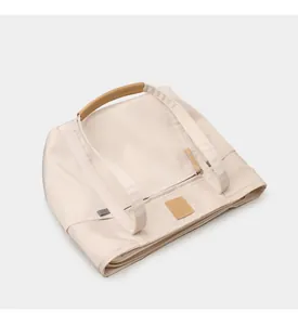 Detail view of beige tote bag with leather handles, zip closure and premium stitching