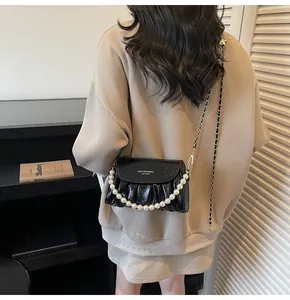 Détail du sac nuage plissé noir avec chaîne en perles et finition en cuir brillant