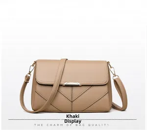 Detail of khaki crossbody bag with V-shaped stitching and gold metal hardware