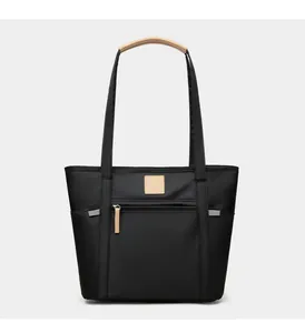Detail of waterproof nylon tote bag with leather accents and large front zipper pocket
