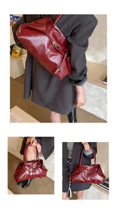 Detail of burgundy textured leather tote bag with soft structure and long shoulder strap