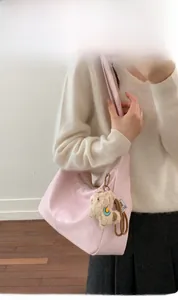 Detail of light pink dumpling bag in glossy leather with a cute plush bear pendant
